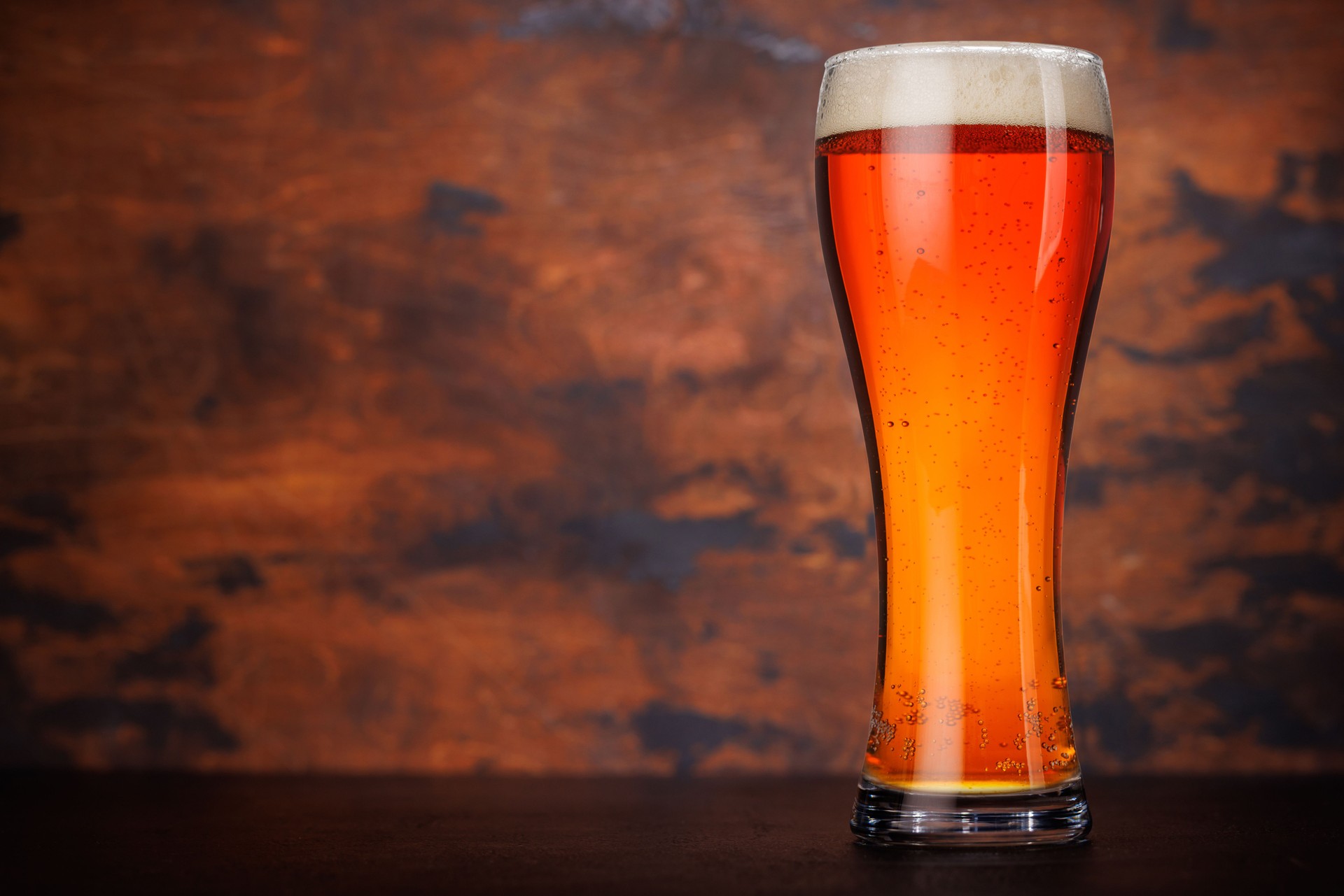 A tall glass of amber beer with frothy head